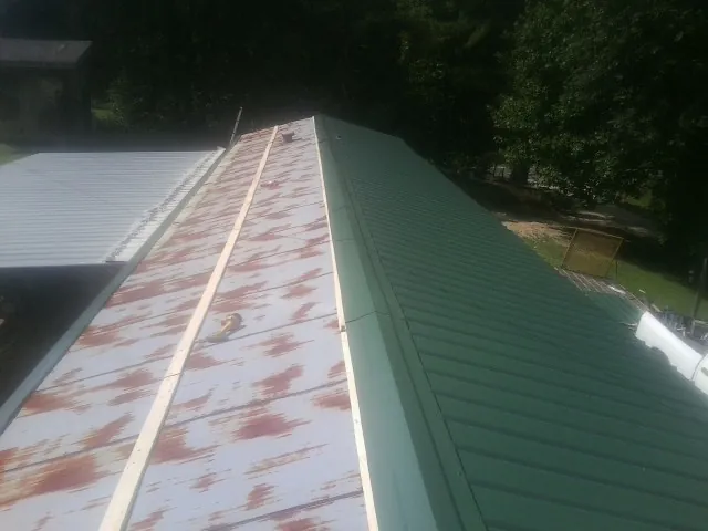 Old rusted panels beside newly installed green metal roofing — Wind Damage Roof Repair by Roofing Brothers in Mead