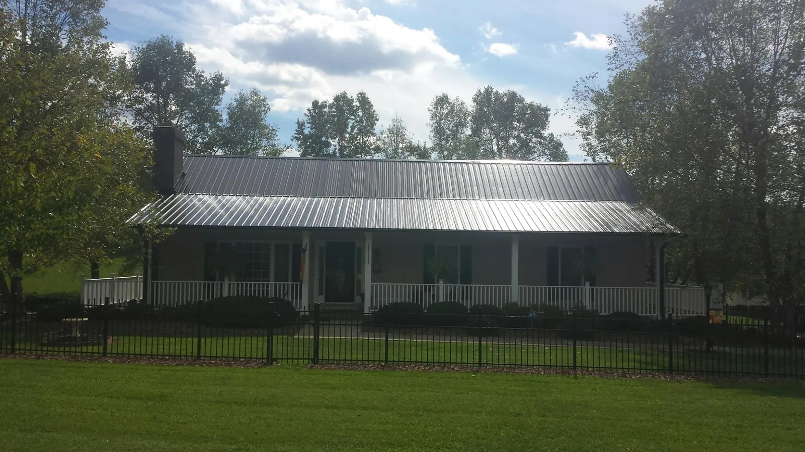 Gray metal roof on a brick ranch with a full width front porch — Gutter Guard Installation work by our crew in Mead